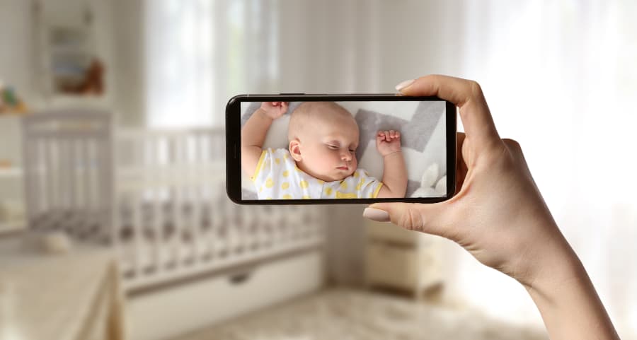 Parent using a smartphone to check on sleeping baby